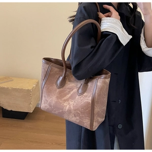Detail view of large brown marble pattern leather tote bag shown on model for daily commute