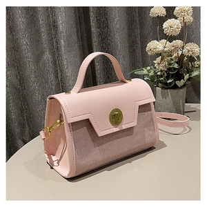 Close-up of pink leather and suede paneling on a square crossbody bag with gold buckle