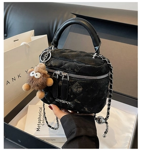Detailed close-up of a black quilted leather vanity bag featuring a silver metal logo and chain