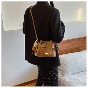 Vue détaillée du sac seau matelassé marron avec détails en cuir et breloque ours