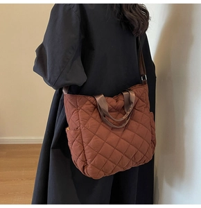 Dettaglio di una borsa tote marrone trapuntata con motivo a rombi e cinghie in tessuto