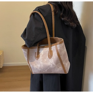 Detail view of large marble texture tote bag with brown straps worn on shoulder