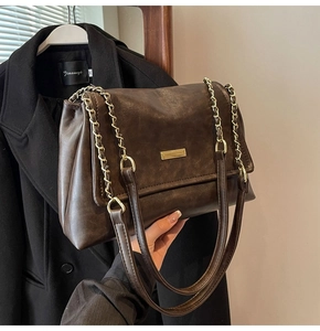 Detail view of the deep brown vintage tote bag with gold metal plaque and chain strap