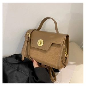 Detail of a brown leather shoulder bag featuring a decorative golden ring metal lock