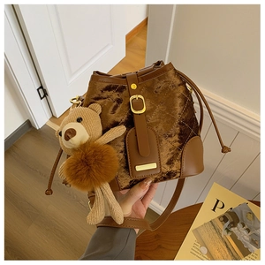 Détail d'un sac seau en velours matelassé marron avec charmant pendentif ours tricoté