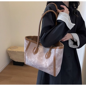 Detail of large tote bag with brown leather trim and textured fabric on shoulder