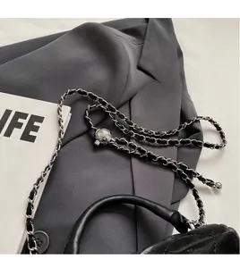 Detail of black quilted leather bucket bag with silver metal ball and chain strap