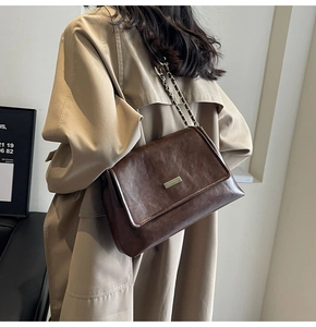 Detail of vintage brown leather tote bag with silver buckle and chain strap on a model