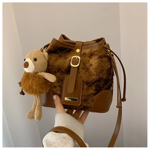 Détail du sac seau matelassé en daim marron avec pendentif ours et cordon de serrage