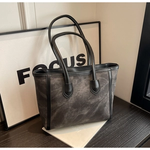 Detail of a large dark grey tote bag with black piping on a modern display tabletop