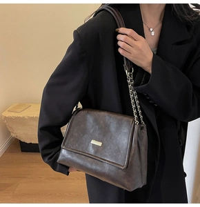 Detail of vintage brown leather crossbody bag with metal buckle and chain strap