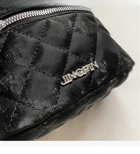 Macro shot of black quilted glossy leather texture and silver metal logo on bucket bag