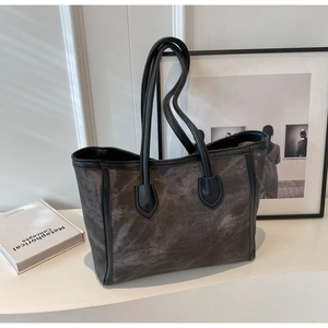 Close-up of a charcoal grey canvas tote bag with black straps in a minimalist studio setting
