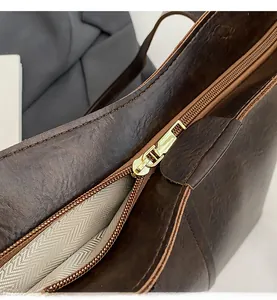 Detail of smooth gold zipper with long leather pull on brown vintage tote bag