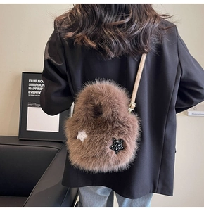 Macro detail of plush brown faux fur bag featuring star patches and a beige leather strap