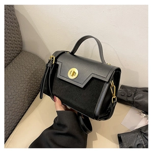 Detail of black crossbody bag with mixed leather texture and golden round swivel lock