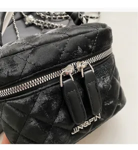 Detail of silver dual zippers and black quilted leather texture on bucket bag