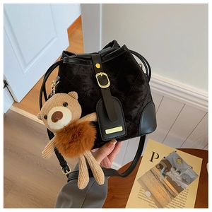 Détail du sac seau en velours noir matelassé avec finitions dorées et bijou d'ours