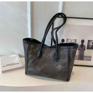 Detailed macro view of charcoal grey tote bag with matte texture and black leather piping