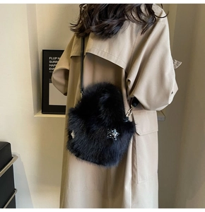 Detail of black faux fur bucket bag with a sparkling star charm on beige trench coat