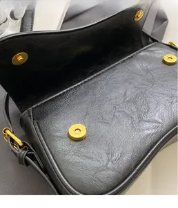Close-up of black retro pleated leather texture and gold magnetic buckle on bag