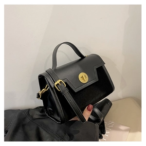 Detail of black contrast texture handbag with gold twist lock and suede panel finish