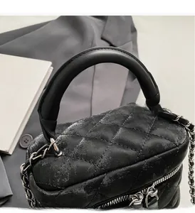 Close-up of black quilted bucket bag featuring silver metal chain and a thick top handle