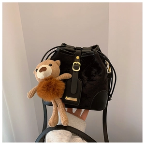 Détail du sac seau en velours noir avec boucle dorée et charm d'ours en peluche tricoté