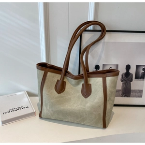 Macro shot of large tote bag featuring beige suede material and dark brown leather trim