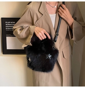 Detail of plush black faux fur bucket bag with a sparkling star accent and leather strap