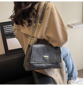 Detail of grey retro leather tote bag with gold metal clasp worn by a model