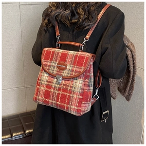 Rear view of a model wearing the red plaid wool backpack with leather trim details