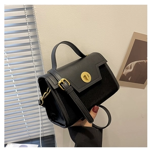 Detail of matte suede and smooth leather textures with a golden rotary lock on a black bag
