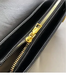 Close-up of premium gold-toned metal zipper on black leather shoulder bag detail