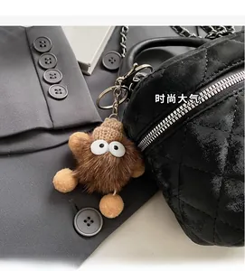 Close-up of a brown monster plush keychain charm on a black quilted chain handbag
