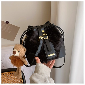 Détail du sac seau en velours noir avec motif matelassé et pendentif ours décoratif