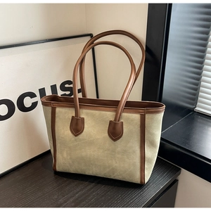 Detail of canvas tote bag showing brown leather stitching and textured fabric