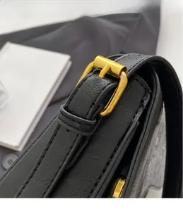 Macro shot of gold rectangular metal buckle on black leather shoulder bag with fine stitching