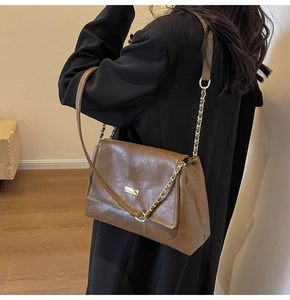 Detail of vintage brown leather bag featuring fine texture and golden metal buckle