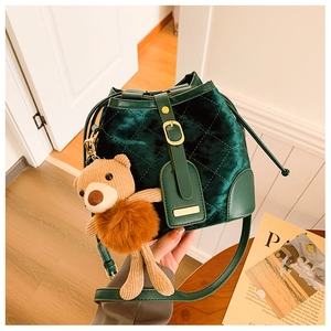 Détail du sac seau en velours vert foncé avec motifs matelassés et breloque ours