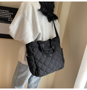 Detailed view of a black quilted tote bag featuring a large rhombus pattern on shoulder