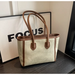Close-up of olive canvas tote bag with brown leather trim on wooden table