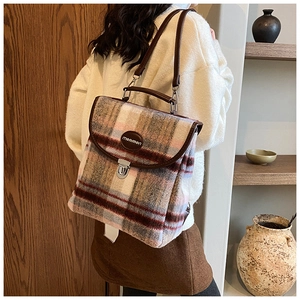Detail of tweed checkered backpack featuring leather trim and a top handle on a female model