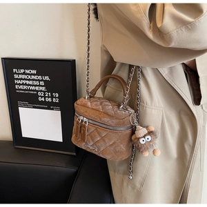 Detail of caramel velvet quilted crossbody bag with chain strap and plush pendant charm