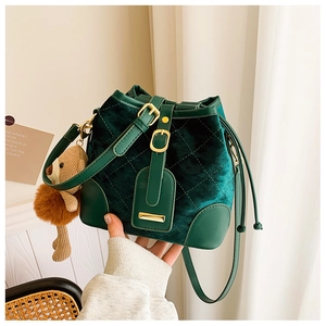 Vue détaillée du sac seau vert foncé avec matelassage en losange et pendentif ours mignon