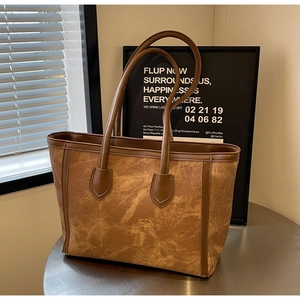 Close-up of brown suede tote bag featuring premium leather handles and neat stitching
