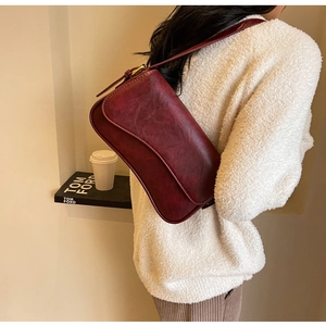 Detailed view of a vintage dark red faux leather underarm bag with magnetic flap closure
