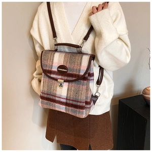 Detailed view of the plaid wool fabric texture and brown leather strap on backpack
