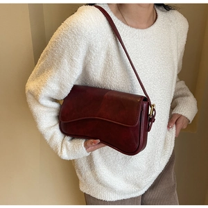 Detail view of deep red vintage shoulder bag with wavy flap and gold metal buckle