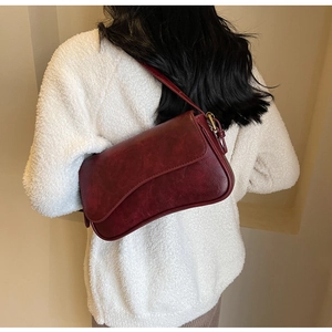 Detailed view of dark red vintage leather texture and strap on a large underarm bag